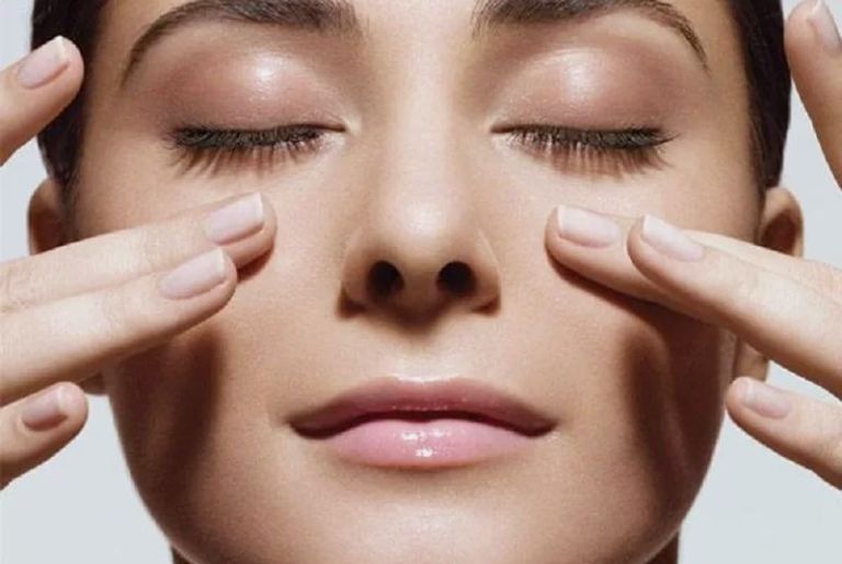 Пальцы на женском лице с закрытыми глазами