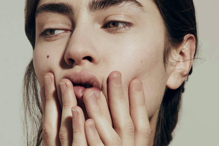 Девушка закрывает лицо и смотрит в сторону