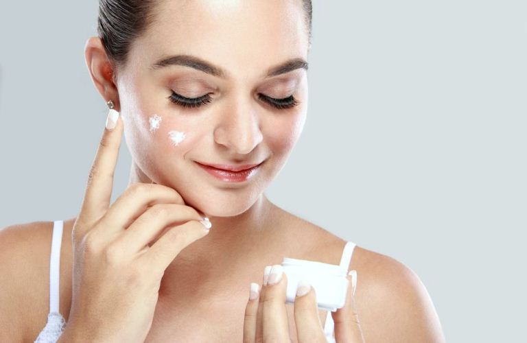 Девушка наносит крем на лицо