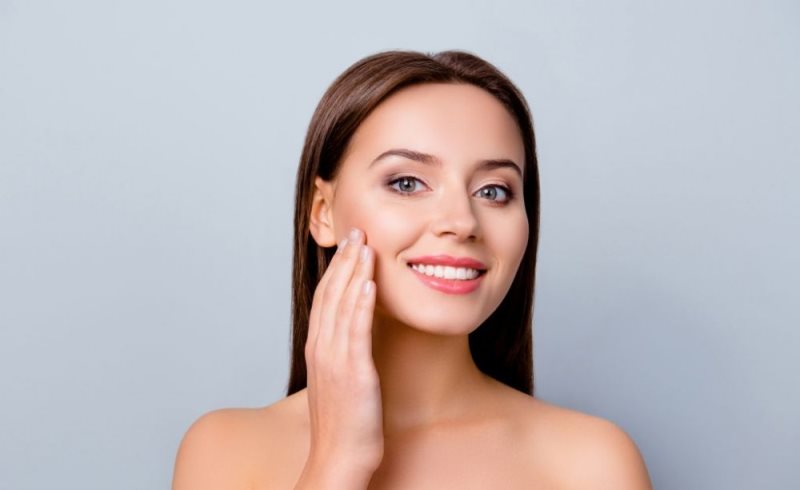 Девушка касается своей щеки