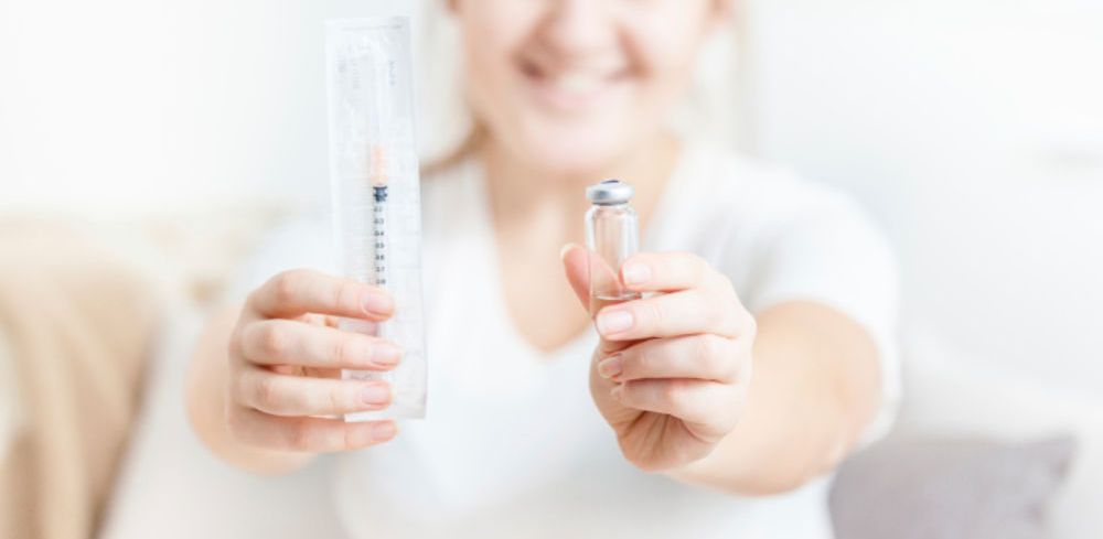 Девушка держит шприц и препарат