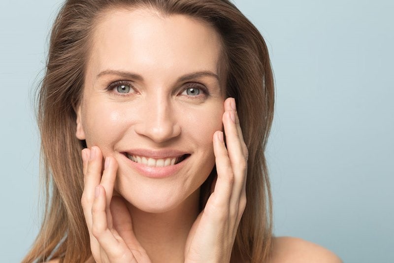 Женщина с сухой кожей касается лица