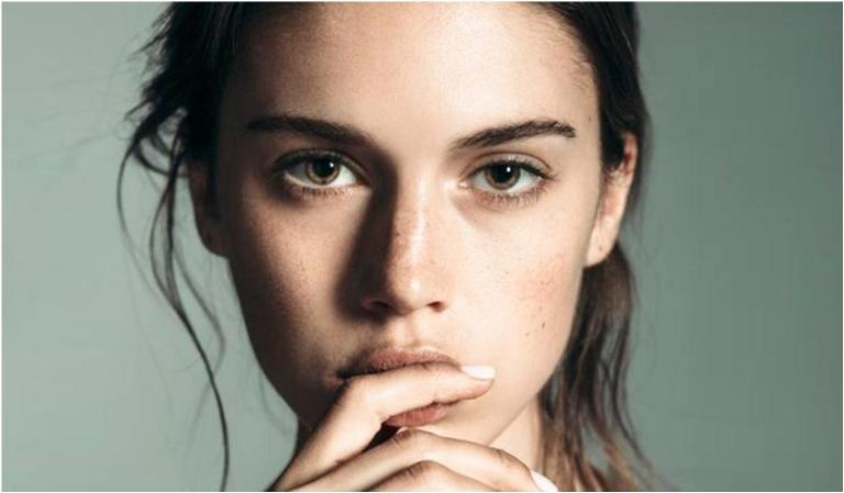 Девушка держит руку возле губ