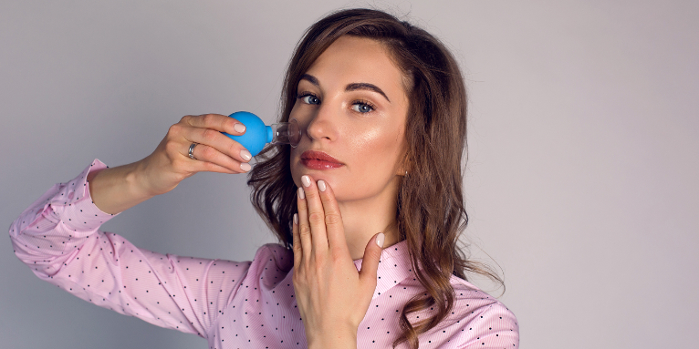 Девушка проводит массаж лица вакуумной банкой