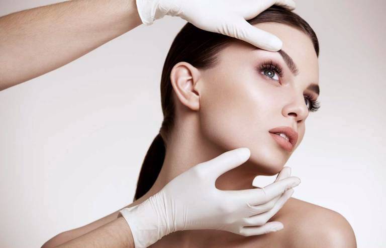 Руки доктора на лице пациента