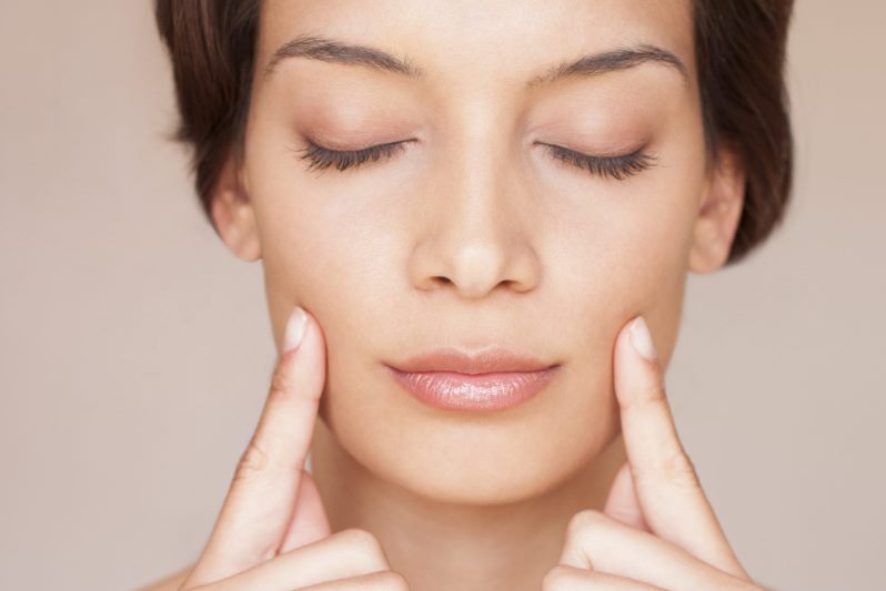 Девушка касается своих щек