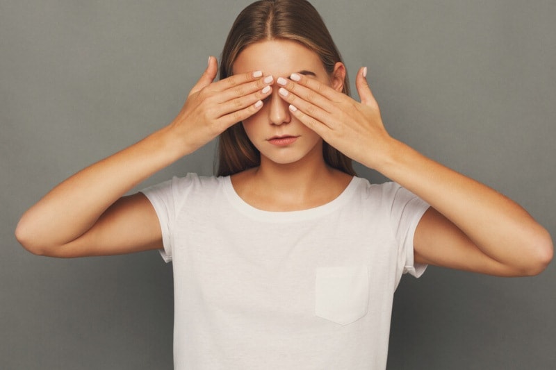 Девушка закрывает глаза руками