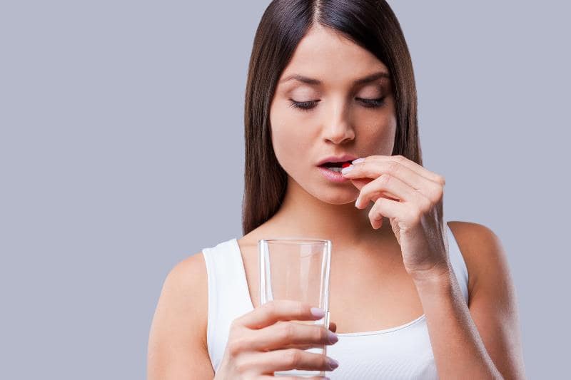 Девушка пьет витамины с гиалуроновой кислотой