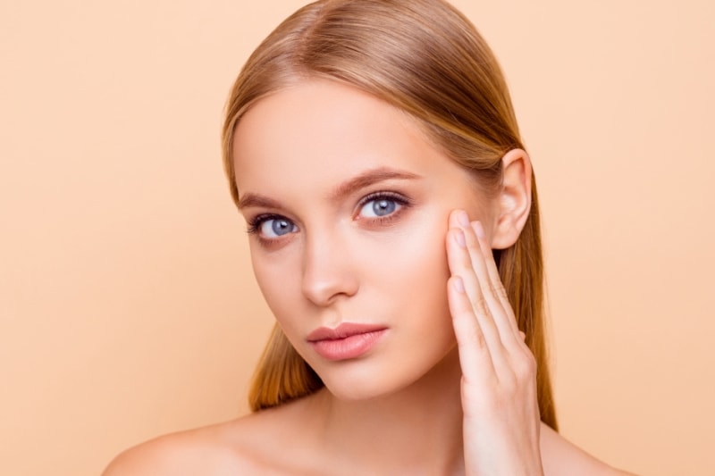 Девушка касается своего лица