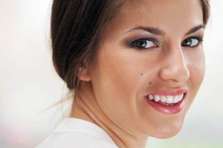 Девушка с родинкой улыбается