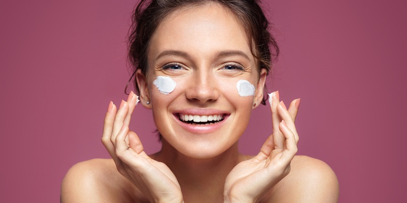 Девушка наносит крем на лицо